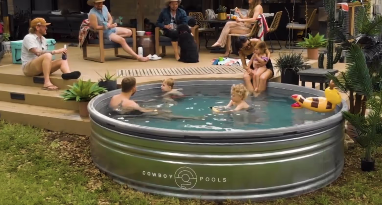 A group of people enjoying a stock tank pool in a backyard setting. 
